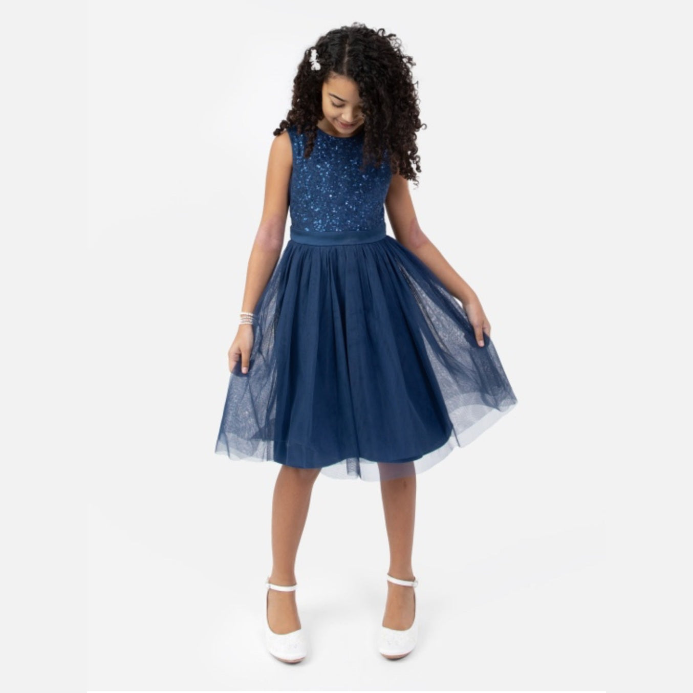 Young girl wearing a navy blue dress with a white background