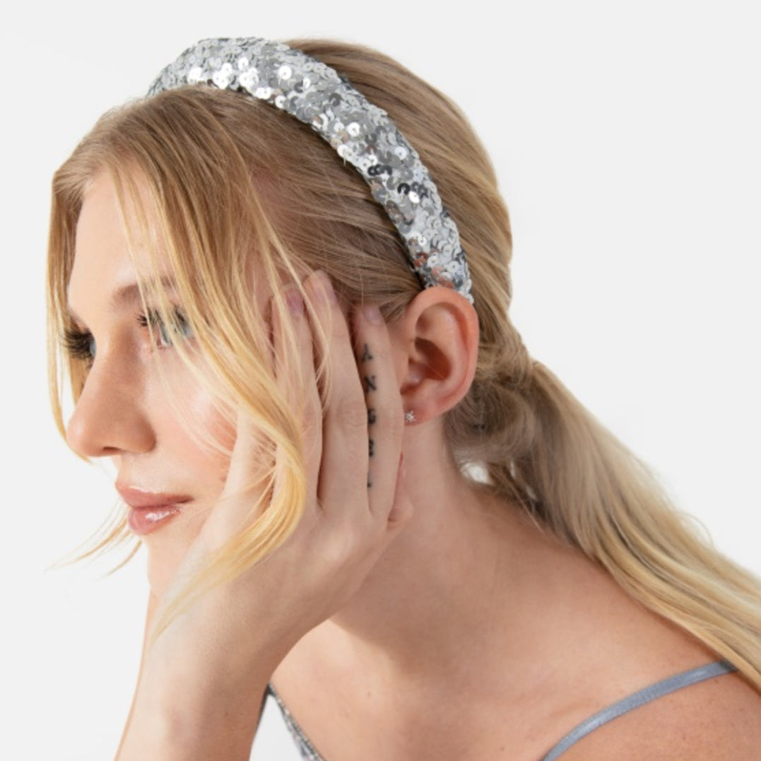 Woman wearing a sparkling silver headband against a white background
